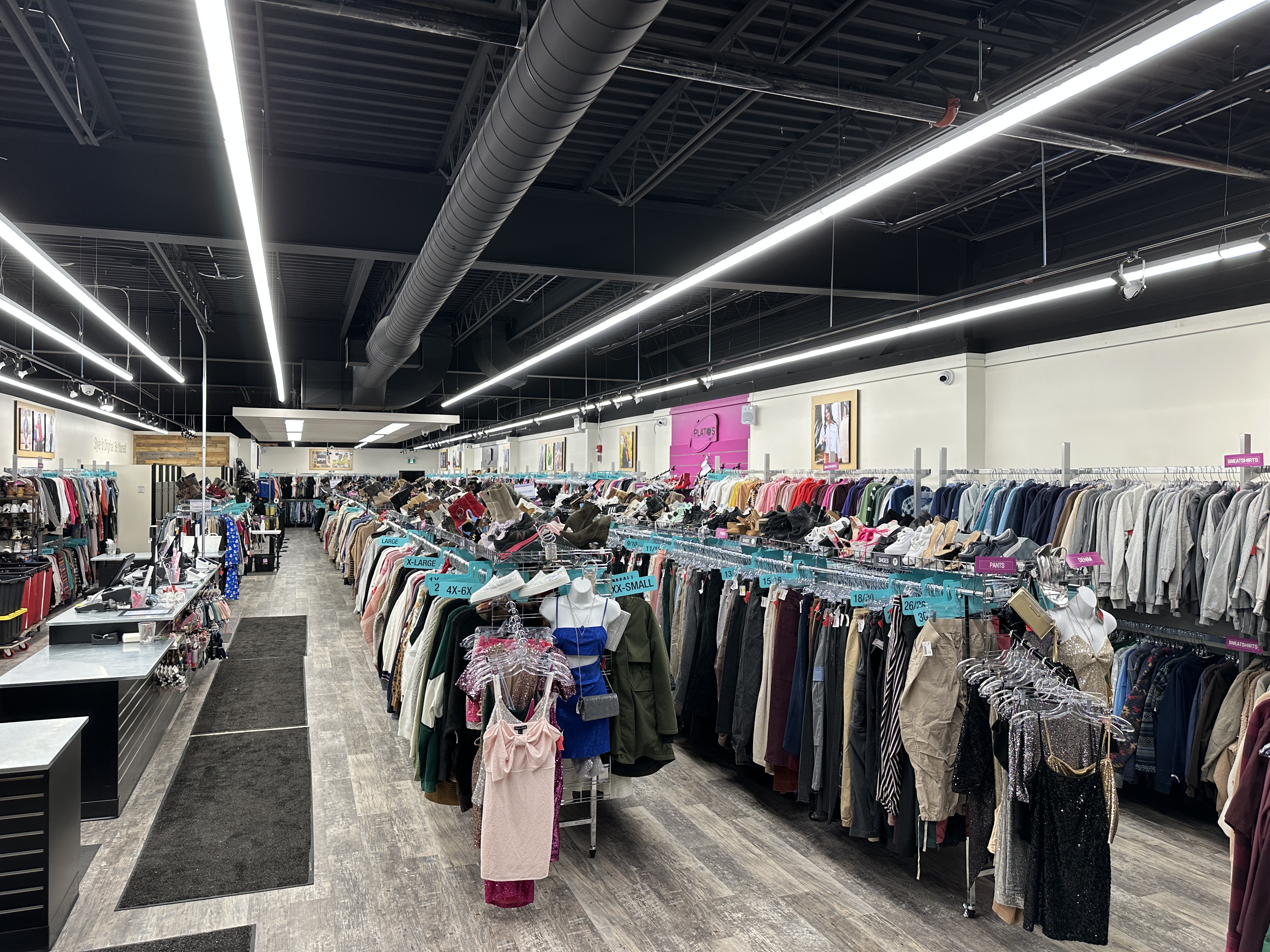 Plato's Closet London North store photo, wide angle from front showing racks of clothes, shoes, the front counter, and the above lights.